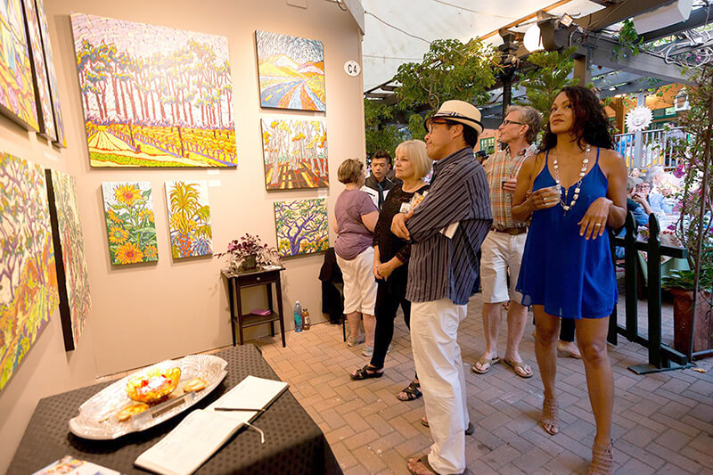 A group of attendees admire art at the Laguna Art-A-Fair event